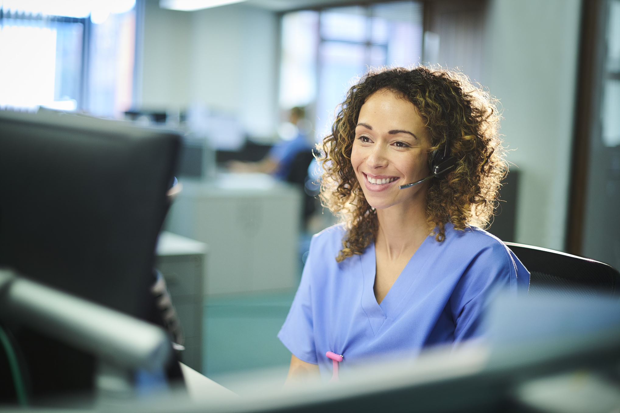 nurse looking at the computer with headphones on