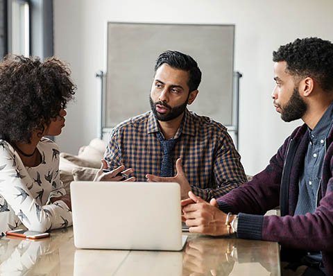 three people having a meeting around a table