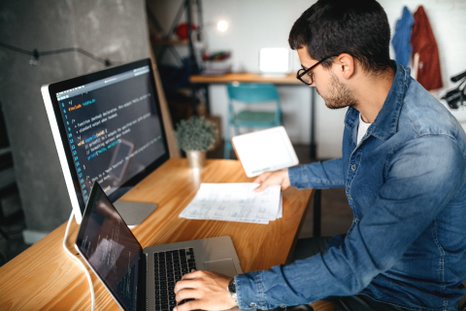 person working on two different screens with codes on it