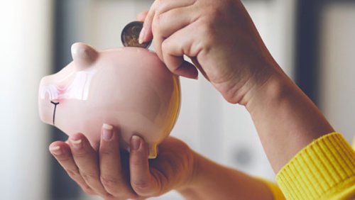 Han holding a piggy bank and putting a coin inside