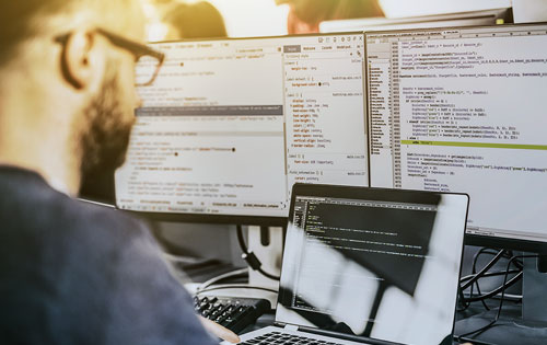 man coding on multiple screens