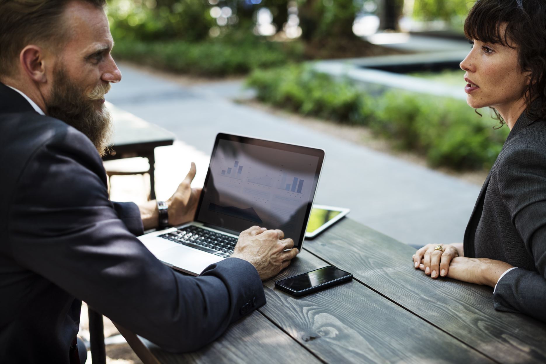 two people talking across each other with a laptop on the table