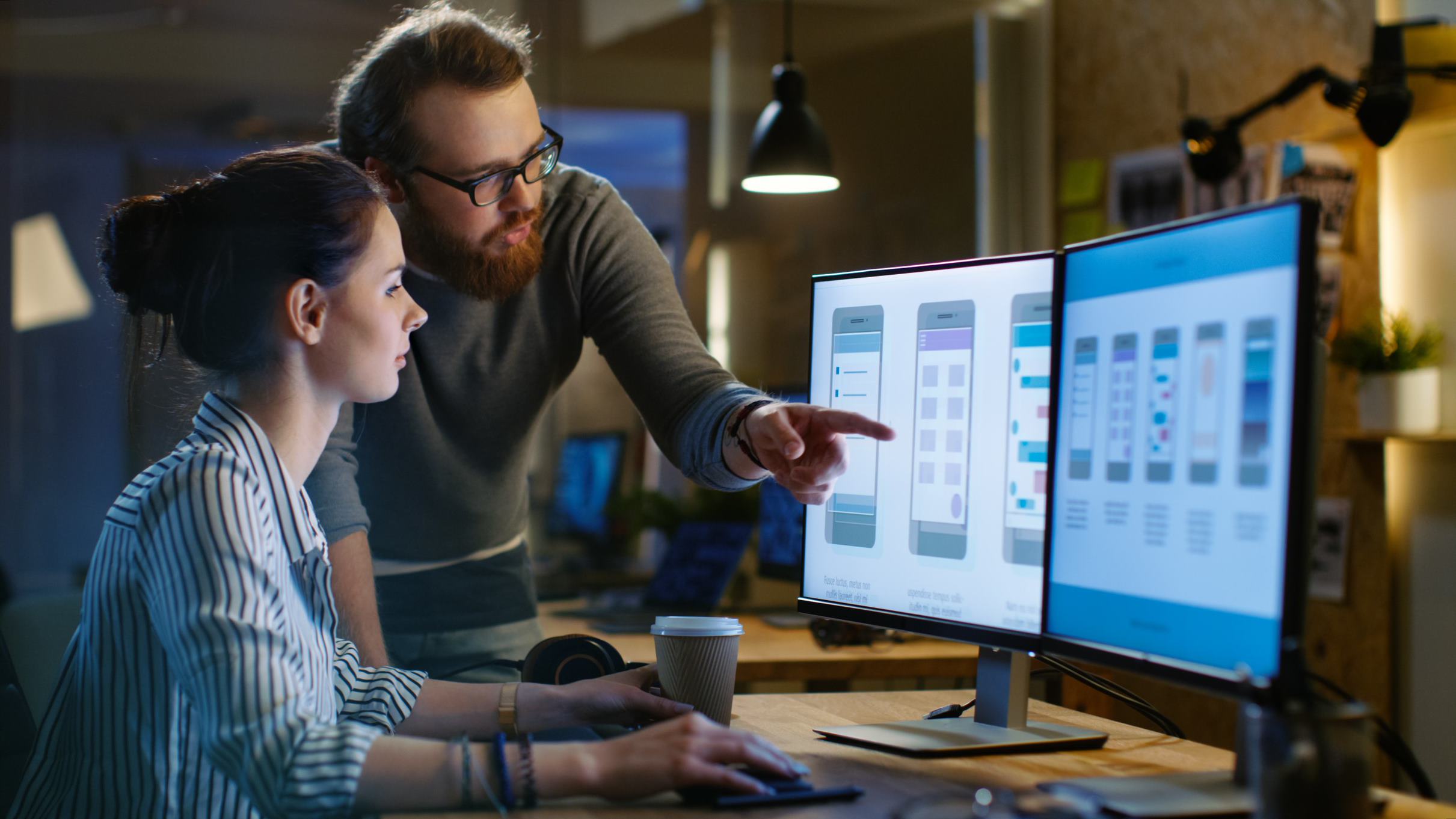 two people pointing at computer screens