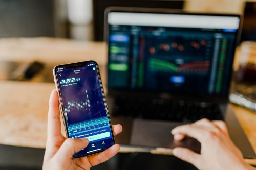 person checking finance on the phone and laptop