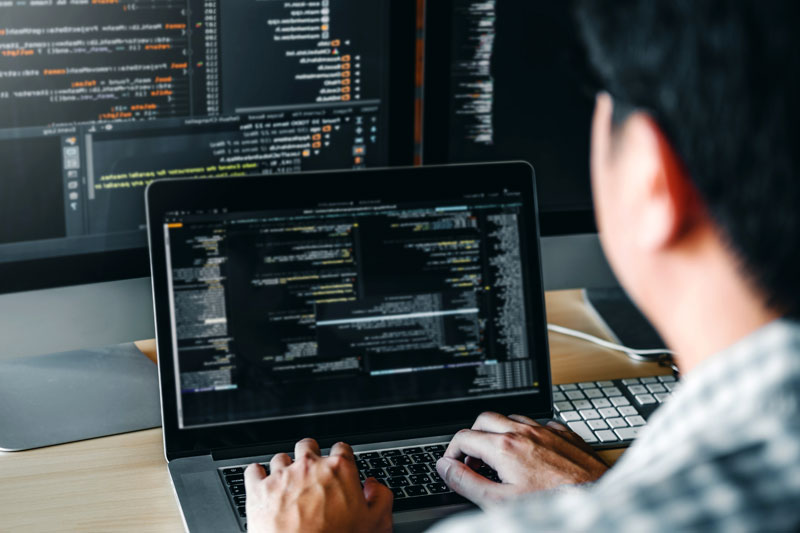 a man typing on a computer with code on the screen