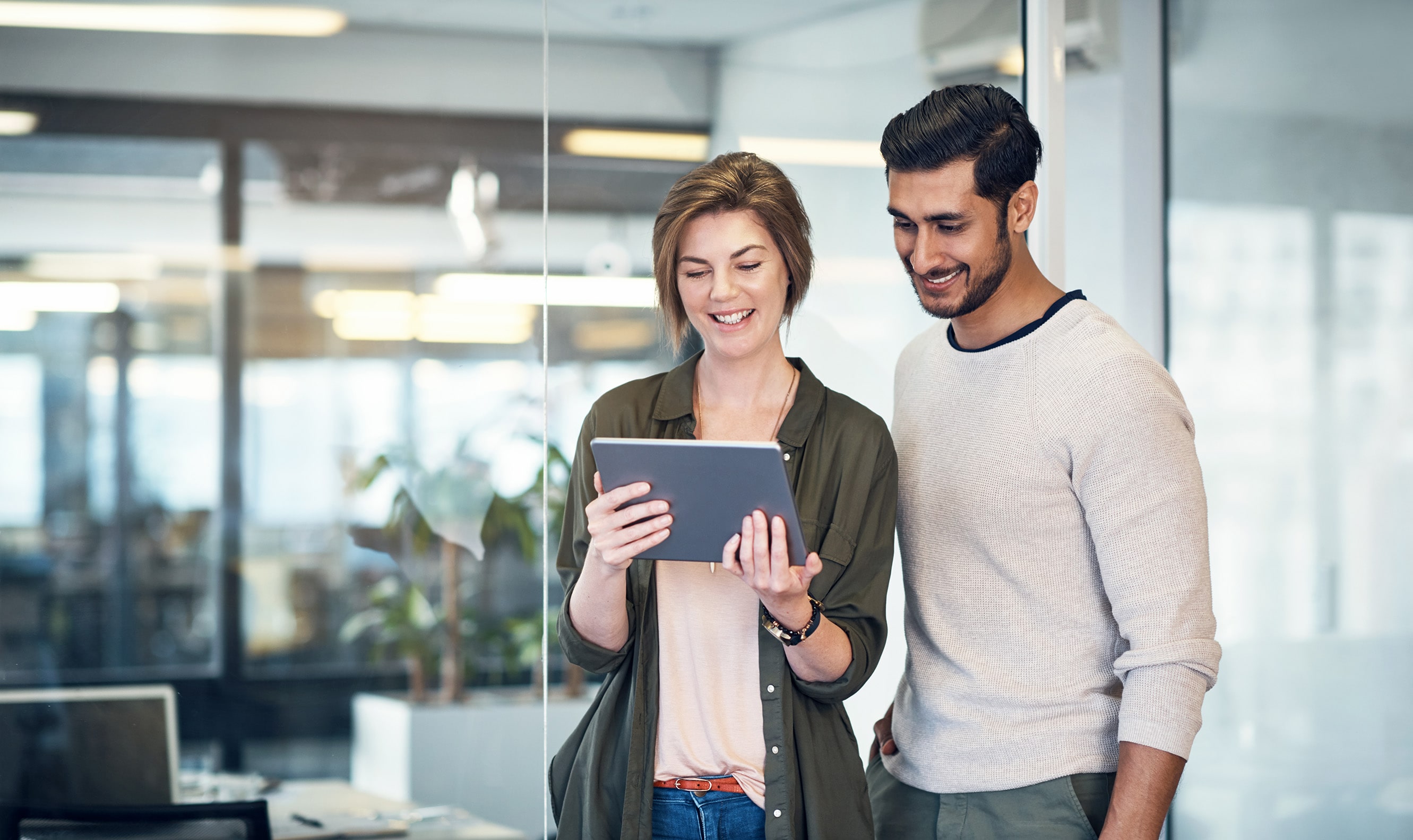Young woman with short hear holding a tablet and showing something to a guy