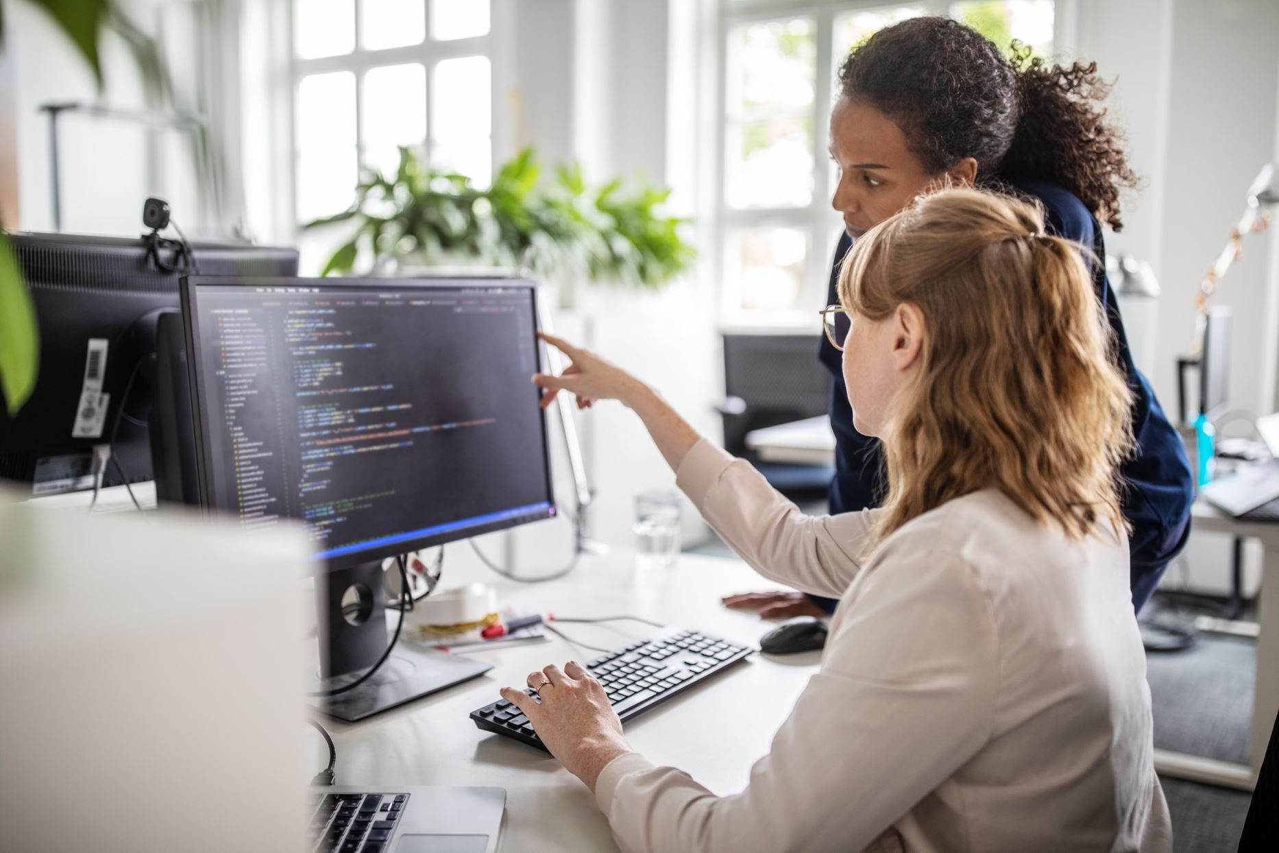 two people pointing at a computer with codes on the screen