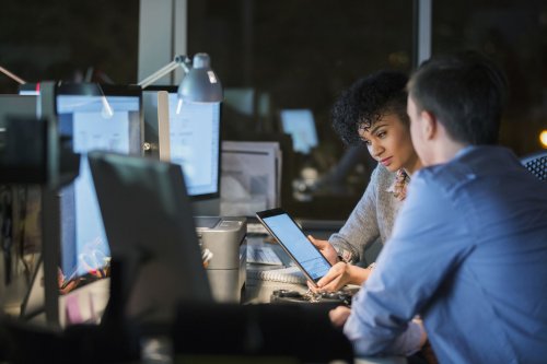 two people looking at a tablet in the office at night