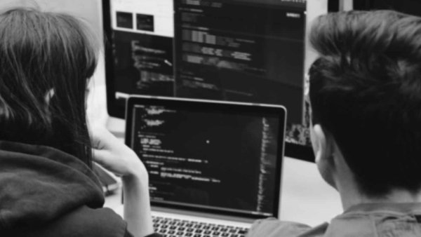 Young woman and man looking at a couple of screens