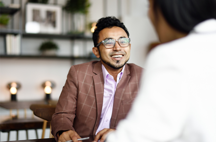 A person in an office smiling while talking with another person