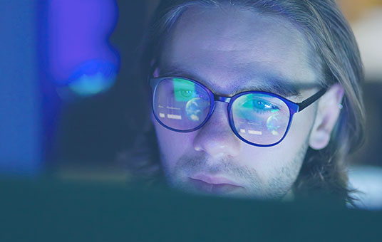 A man with glasses looking at a screen