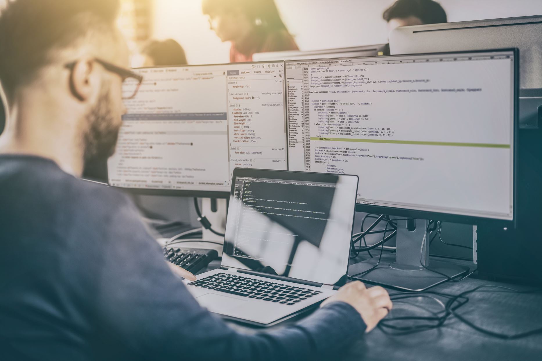 person working on multiple screens with codes
