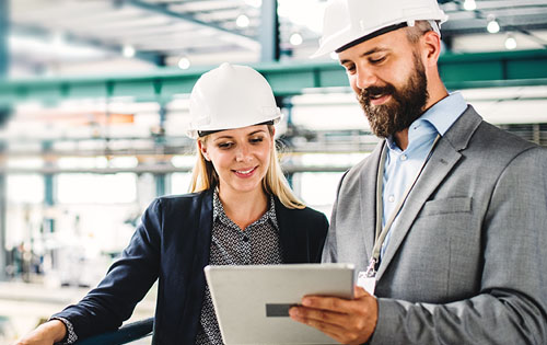 two people in a factory with helmets