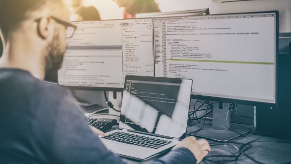 man working on multiple computers